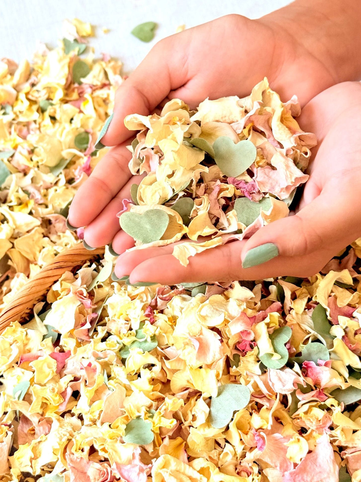 Colorful natural wedding petal confetti blends in bowls and paper cones on warm ivory linen