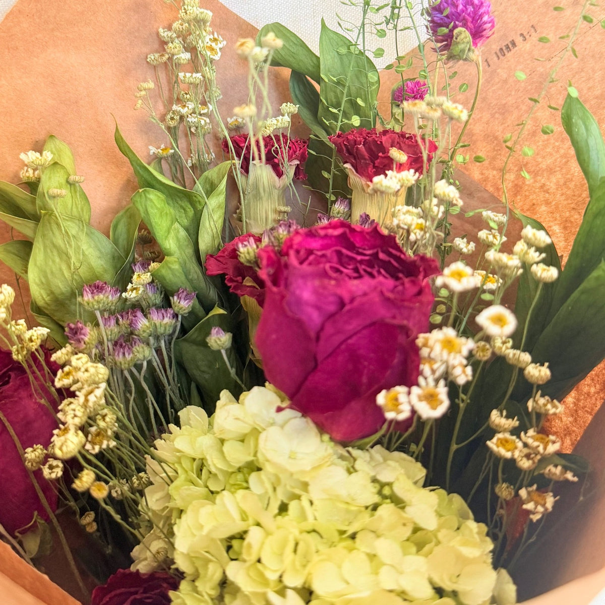 Close-up of Gathered Meadow showing berry roses, pale hydrangea, petite flowers, and green foliage