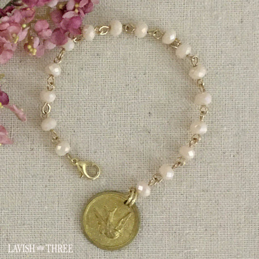 Gold bird charm on pale peach flesh color beaded bracelet lavish three 3